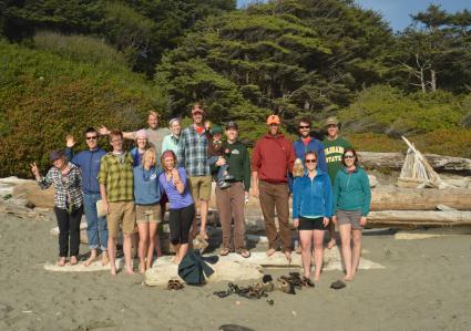 A large group of students and staff with their families at the beach