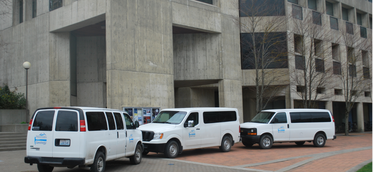 The lower level of the environmental sciences building with white vans parked out front