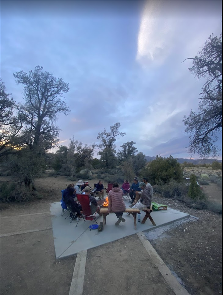 Students sit around a campfire in the evening