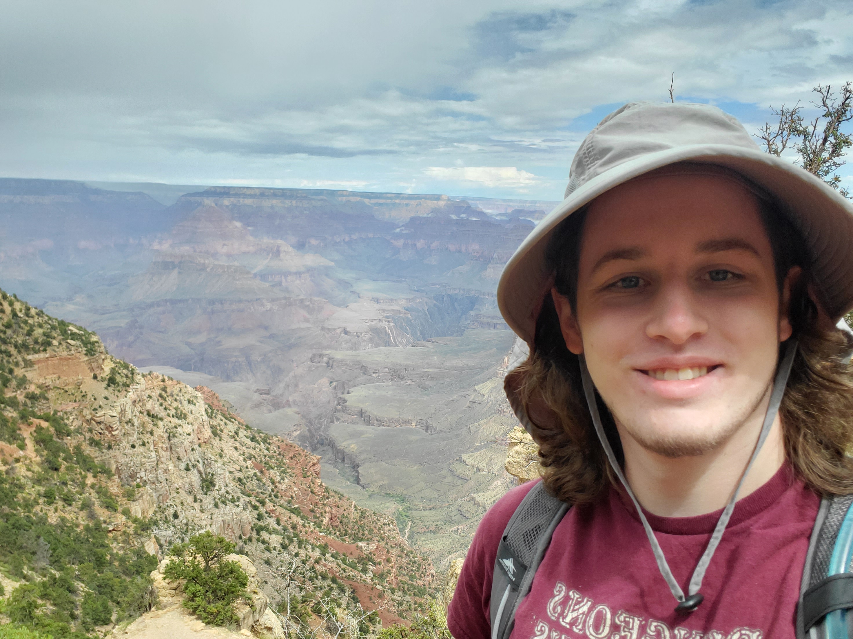 Avery in a grey sun hat with the grand canyon behind him